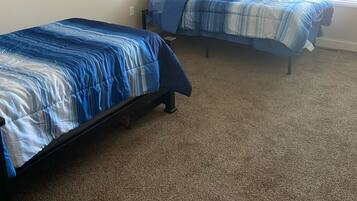 Ein Schlafzimmer mit zwei Einzelbetten, beige gestrichenen Wänden und Teppichboden.