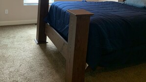 Un dormitorio con una cama, una ventana con persianas, un ventilador de techo y una mesita de noche.