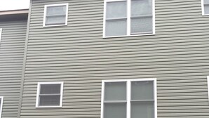 Un edificio de varios pisos con fachada gris, múltiples ventanas y dos puertas de garaje.