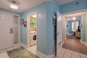 A laundry room with a washing machine, a dryer, and a shelf with cleaning supplies.