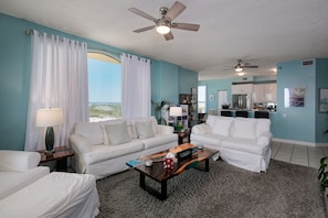 A living room with a sofa, coffee table, and ceiling fans.