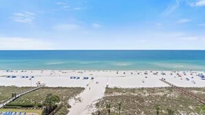 A beach with a clear sky, a sandy shore, and a pathway leading to the water.
