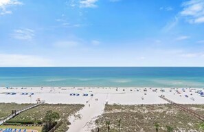 A beach with a clear sky, a sandy shore, and a pathway leading to the water.