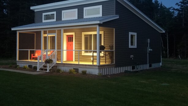 A two-story house with a covered porch, a red door, and a small outdoor seating area. - #1 Misty Mountain View Home near Cabot Trail, Margaree river access (Margaree Valley)