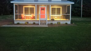 A two-story house with a covered porch, a red door, and a small front yard. - #1 Misty Mountain View Home near Cabot Trail, Margaree river access (Margaree Valley)