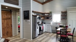 A modern kitchen with a built-in oven, refrigerator, and microwave. There is a dining area with a table and chairs. - #1 Misty Mountain View Home near Cabot Trail, Margaree river access (Margaree Valley)
