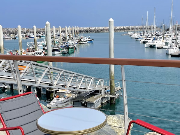 A marina with boats docked, a metal railing, and a table with a chair.