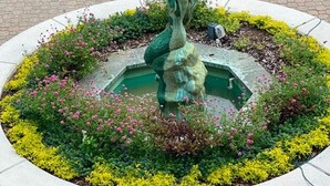A circular garden with a central fountain and statue, surrounded by a variety of plants and flowers. - Lovely Villa Just Steps From The Harbour (Hilton Head Island)