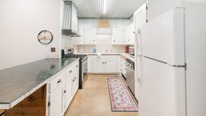 Een keuken met witte kastjes, een fornuis en een koelkast.