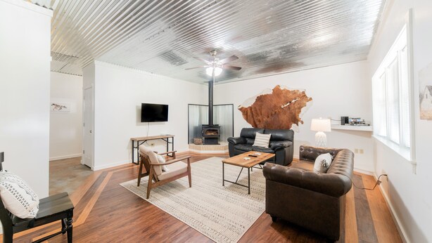 Een ruime woonkamer met een hoge plafond, een grote houten salontafel, een leren bank en een moderne open haard.