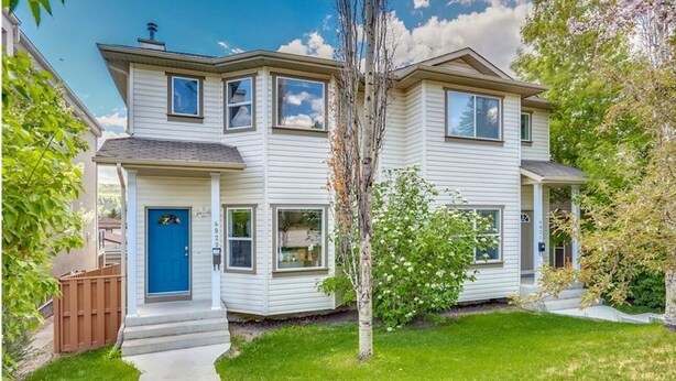 A two-story residential building with a front entrance, a visible mailbox, and a small front yard with a tree and a fence. - Awesome Summer or Stampede Rental (Calgary)