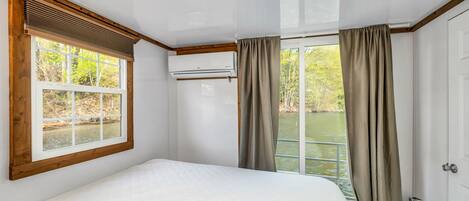 Ein Schlafzimmer mit einem großen Bett, einem Fenster mit Flussblick und einem an der Wand befestigten Feuerlöscher.