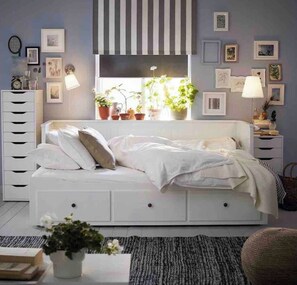 Cozy retreat with a central bed, framed artwork, and lush greenery.