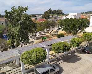 A parking area with a white car, a pedestrian pathway, and trees.