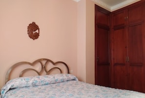 A bedroom with a bed, a wooden wardrobe, and a wall-mounted decoration.