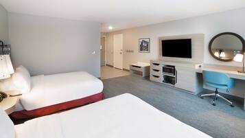 A hotel room with two beds, a desk, a chair, a TV, and a mirror.