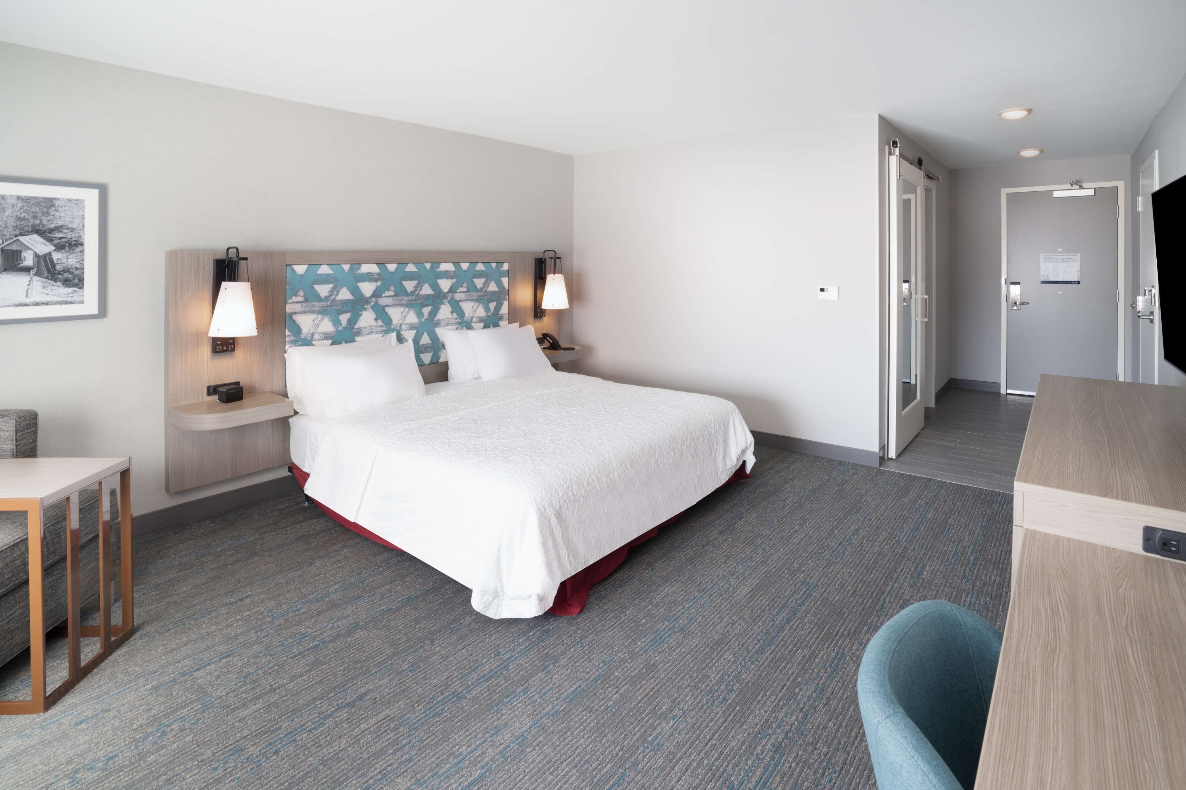 A hotel room with a large bed, bedside lamps, a desk, and a chair.
