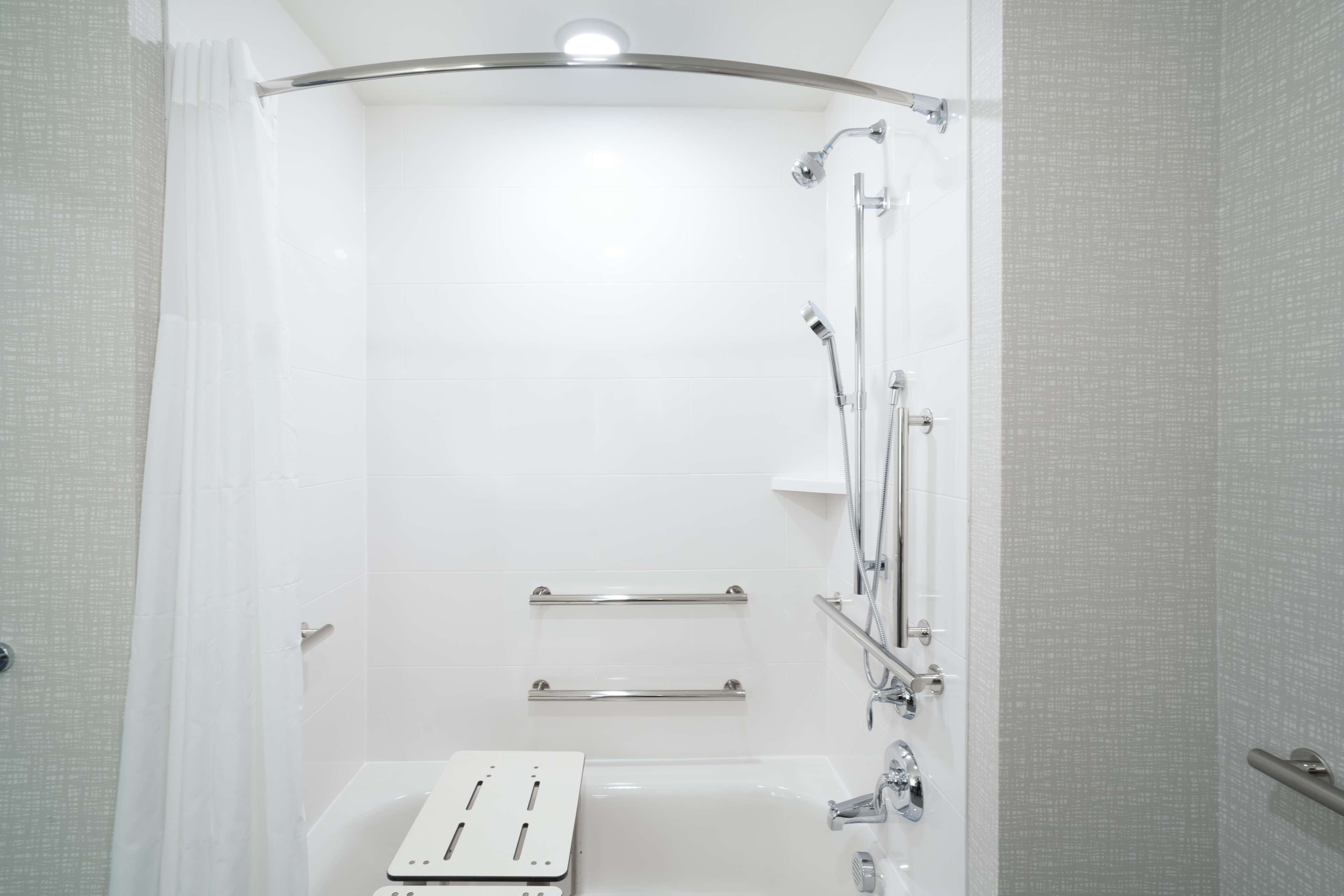 A modern bathroom with a walk-in shower, grab bars, and a bathtub.
