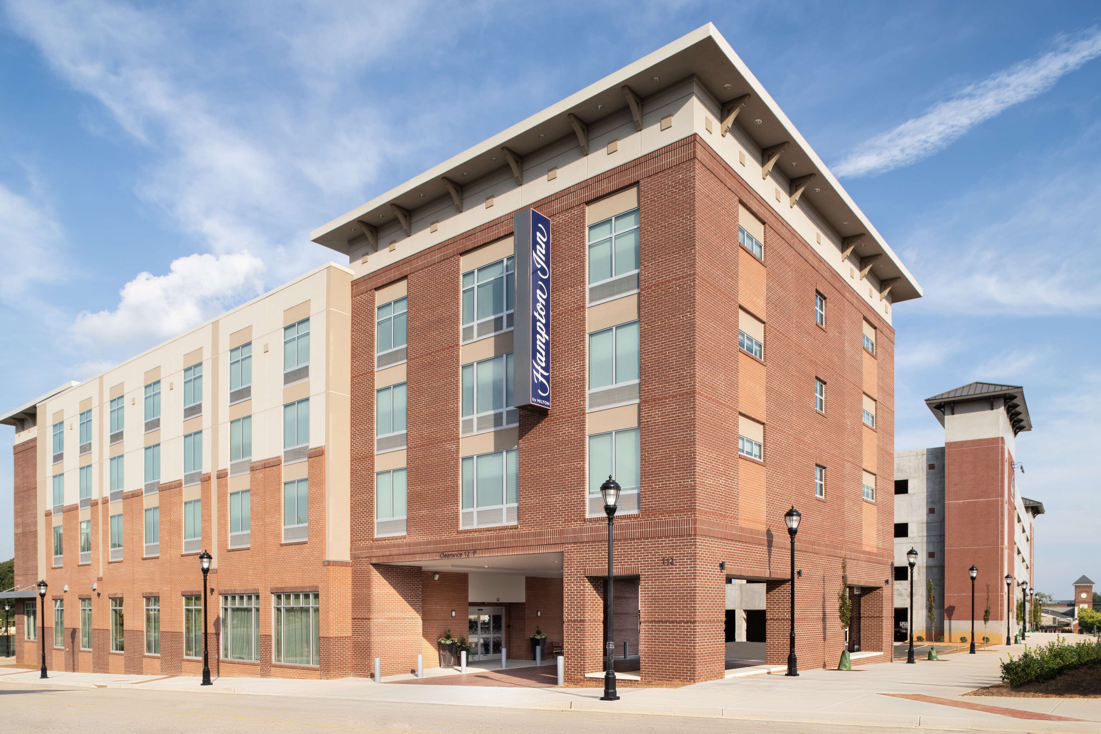 A modern hotel with a brick facade, large windows, and a clear sky.