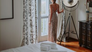 A room with a bed, a standing lamp, a window with curtains, and a dresser. - Villa Laura (Gardone Riviera)