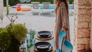 A dining area with a table set for four, outdoor seating, and a pool in the background. - Villa Laura (Gardone Riviera)