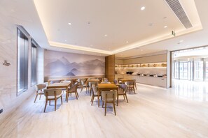 Un moderno comedor con mesas y sillas, una encimera de cocina y un mural de montañas en la pared.