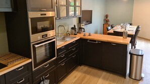 A modern kitchen with dark cabinetry, stainless steel appliances, and a wooden countertop.