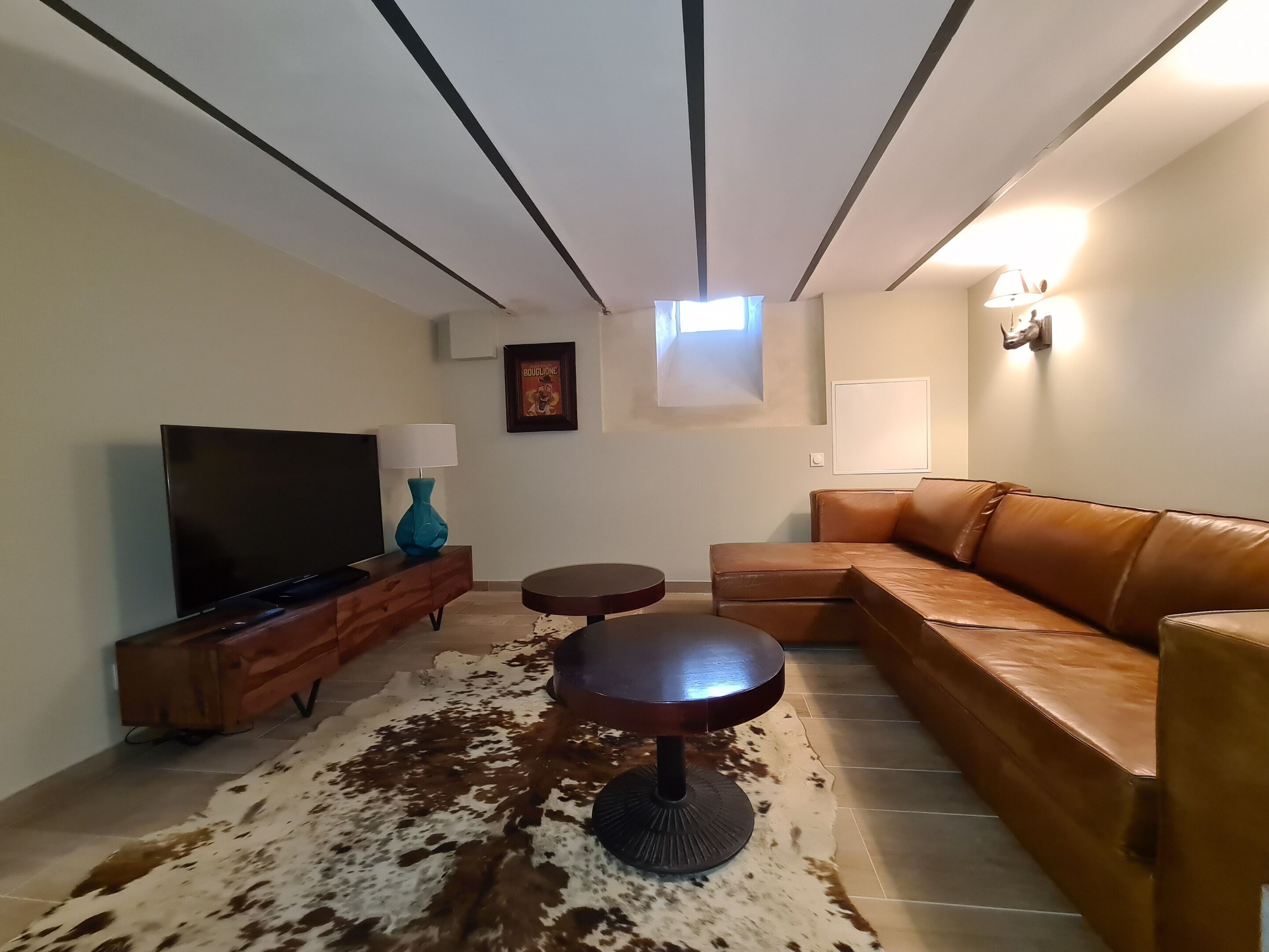 Een woonkamer met een modulaire bank, een flatscreen televisie, een salontafel en een decoratieve vaas.