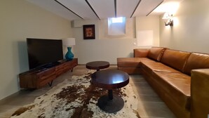 A living room with a sectional sofa, a flat-screen TV, a coffee table, and a decorative vase.