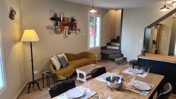 Een eetgedeelte met een houten tafel voor vier personen, een bank en een trap naar een hoger niveau.