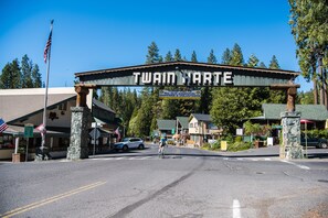 Ein Schild mit der Aufschrift "TWIN HARTE" über einem Straßeneingang, im Hintergrund ein Radfahrer, Autos und Gebäude.