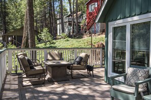 Relax on the deck with comfortable lounge chairs and a bench, surrounded by a lush wooded area and a distant view.