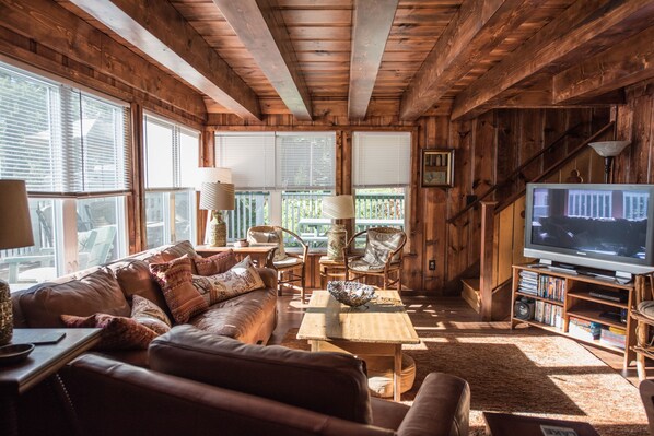 Relax in this inviting living room with a comfortable sofa, wooden coffee table, and large windows.