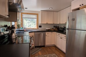 Enjoy cooking in this well-equipped kitchen with stainless steel appliances, white cabinetry, and a large window.