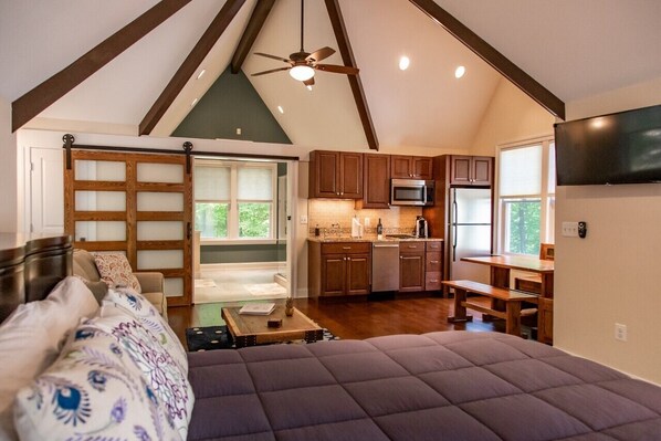 A bedroom with a large bed, a wooden door, and a ceiling fan.
