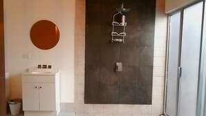 A modern bathroom with a large dark tiled wall, a white sink, and a mirror. - Executive Studio - 15 min. from US Consulate | Flexible Check-in (Ciudad Juárez)