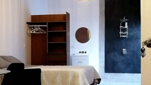 A bedroom with a bed, a wardrobe, a round mirror, and a door with a key hook. - Executive Studio - 15 min. from US Consulate | Flexible Check-in (Ciudad Juárez)