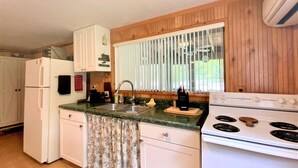 Una cocina compacta con refrigerador, estufa, lavamanos y paneles de madera.