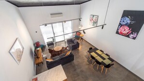 A modern loft-style living space with a high ceiling, large windows, and a dining area. - Vasse New-Yorker Townhouse (KEALY)