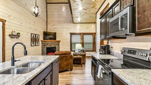 A kitchen with granite countertops, stainless steel appliances, and a stone fireplace.