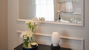 Ett modernt badrum med en stor spegel, en vas med blommor och en unik, sfärisk lampa.