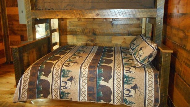 A wooden bunk bed with a patterned bedspread and pillows. - Post and beam cabin with bunk beds (Shirley Mills)