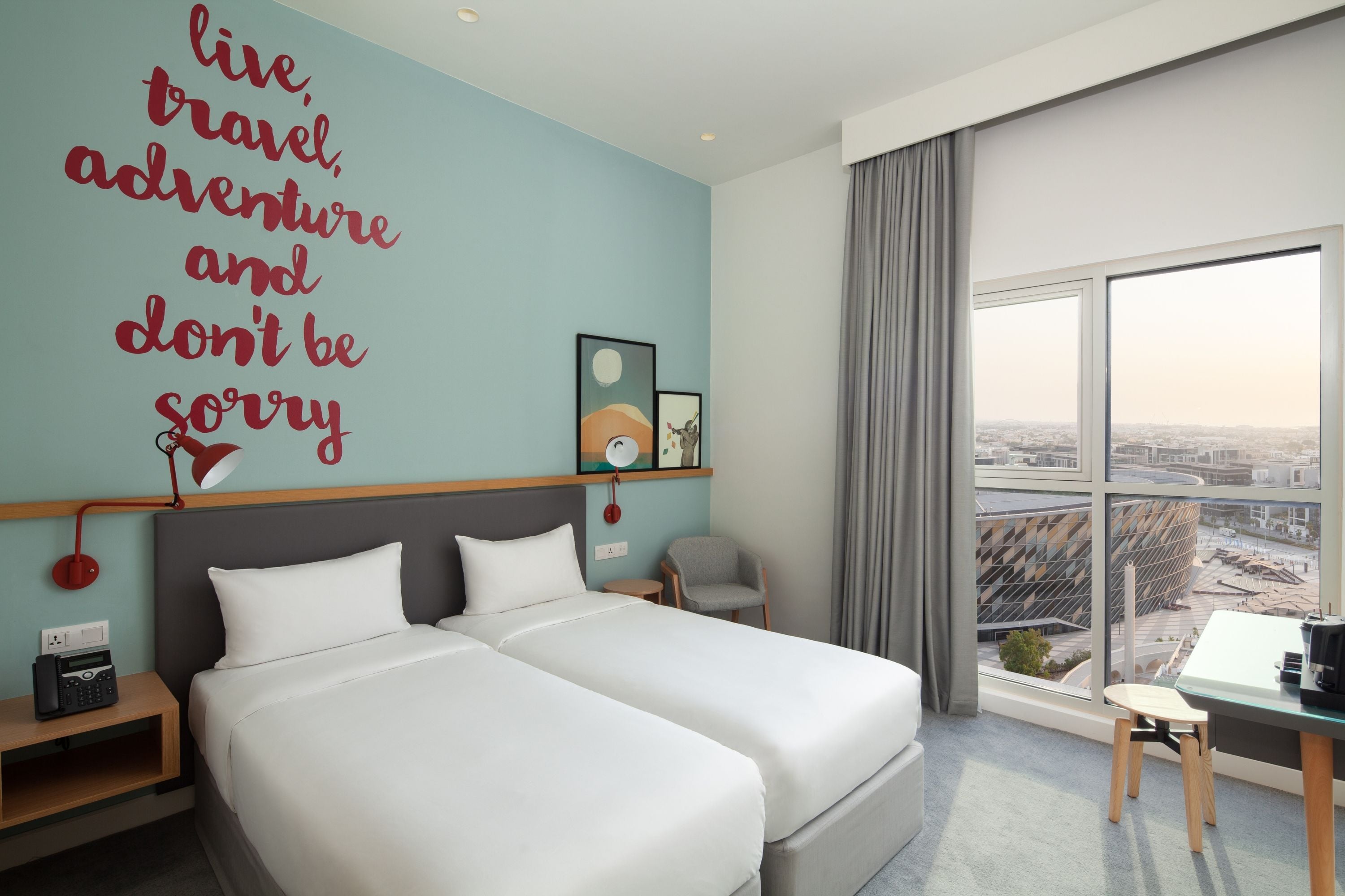 Habitación de hotel con una cama grande, un escritorio y vistas a la ciudad.