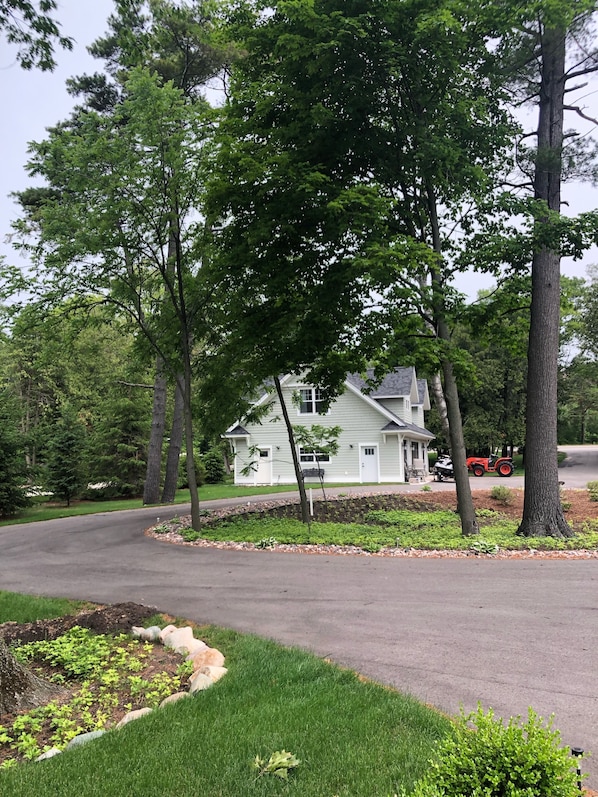 A residential area with a house, a driveway, and a lawn. - North Lake Leelanau carriage/cottage. Sandy beach front on North Lake Leelanau. (Leland)