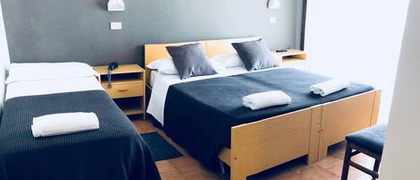 A hotel room with two single beds, a wooden nightstand, a desk, and a chair.