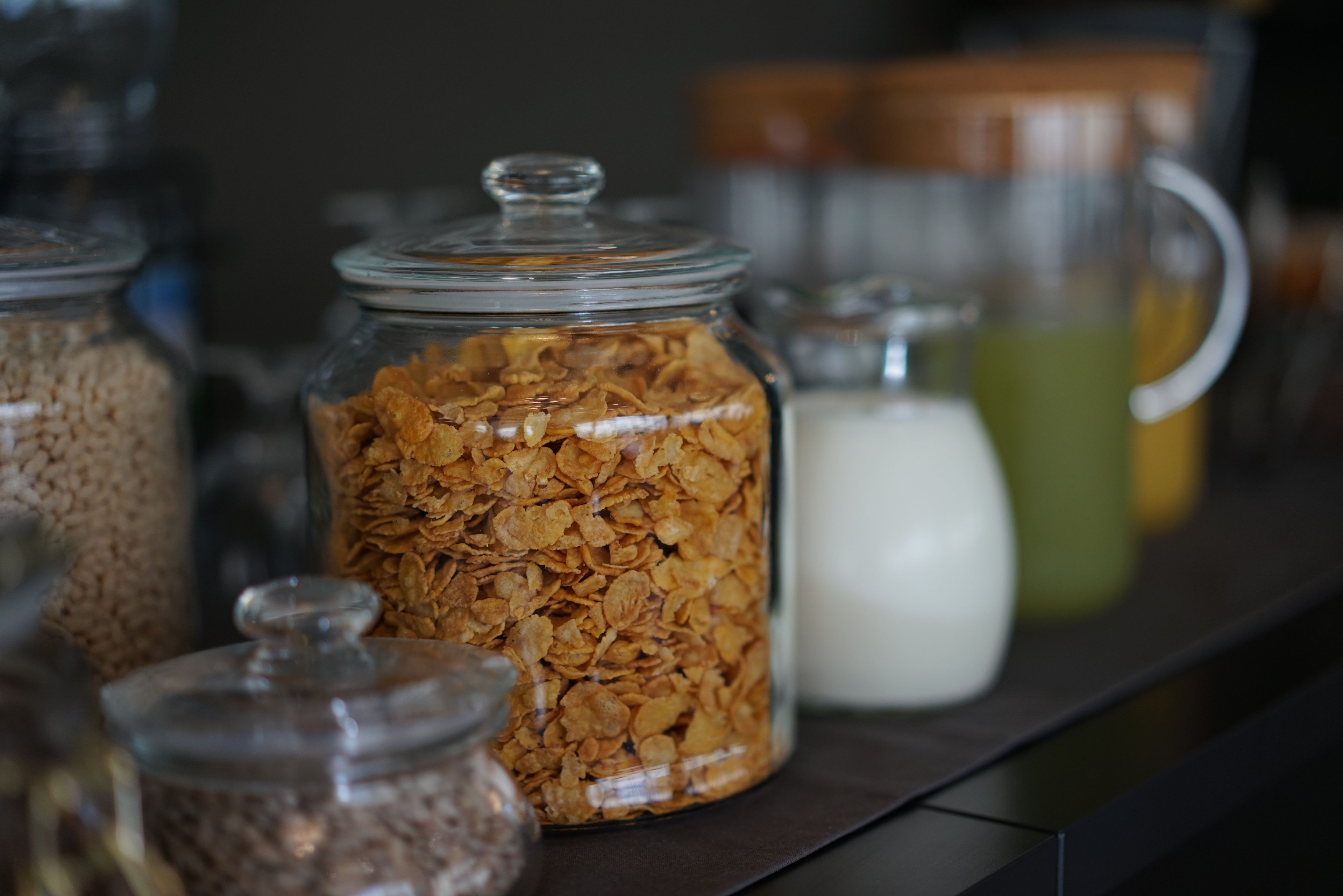 A shelf with glass jars containing various grains and a milk jug.