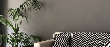 A modern living room with a sofa and a large potted plant.