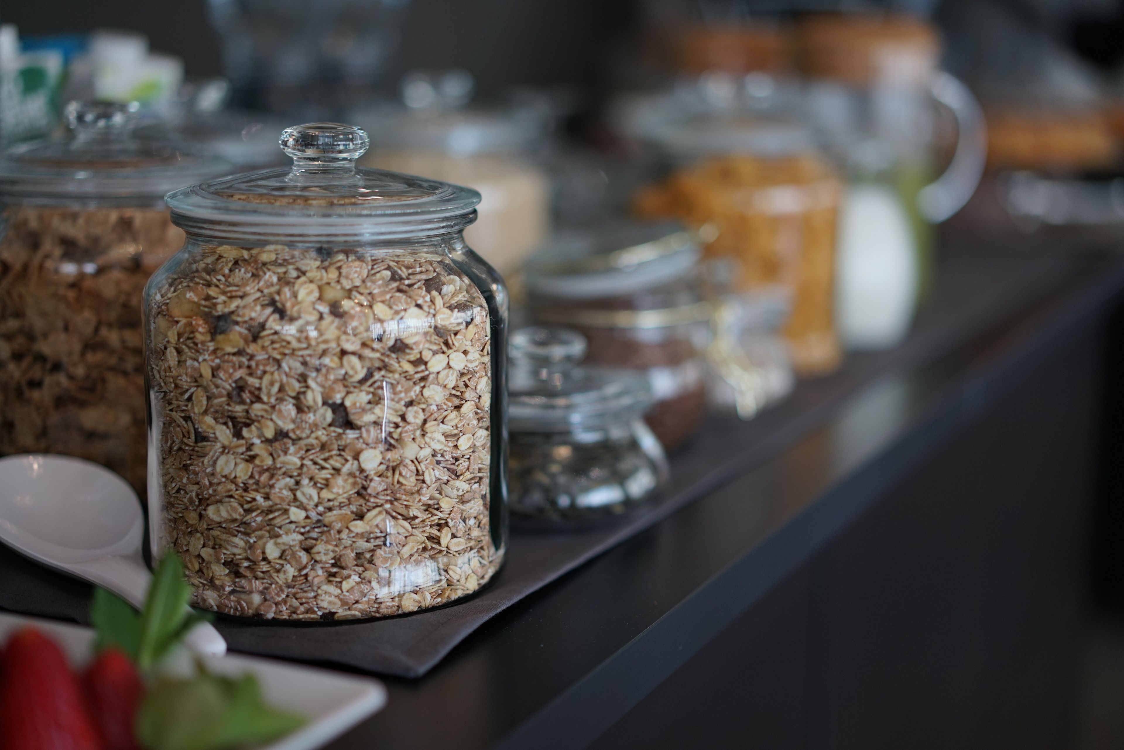 A breakfast bar with glass jars of granola and other breakfast items.