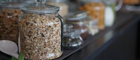 A breakfast bar with glass jars of granola and other breakfast items.
