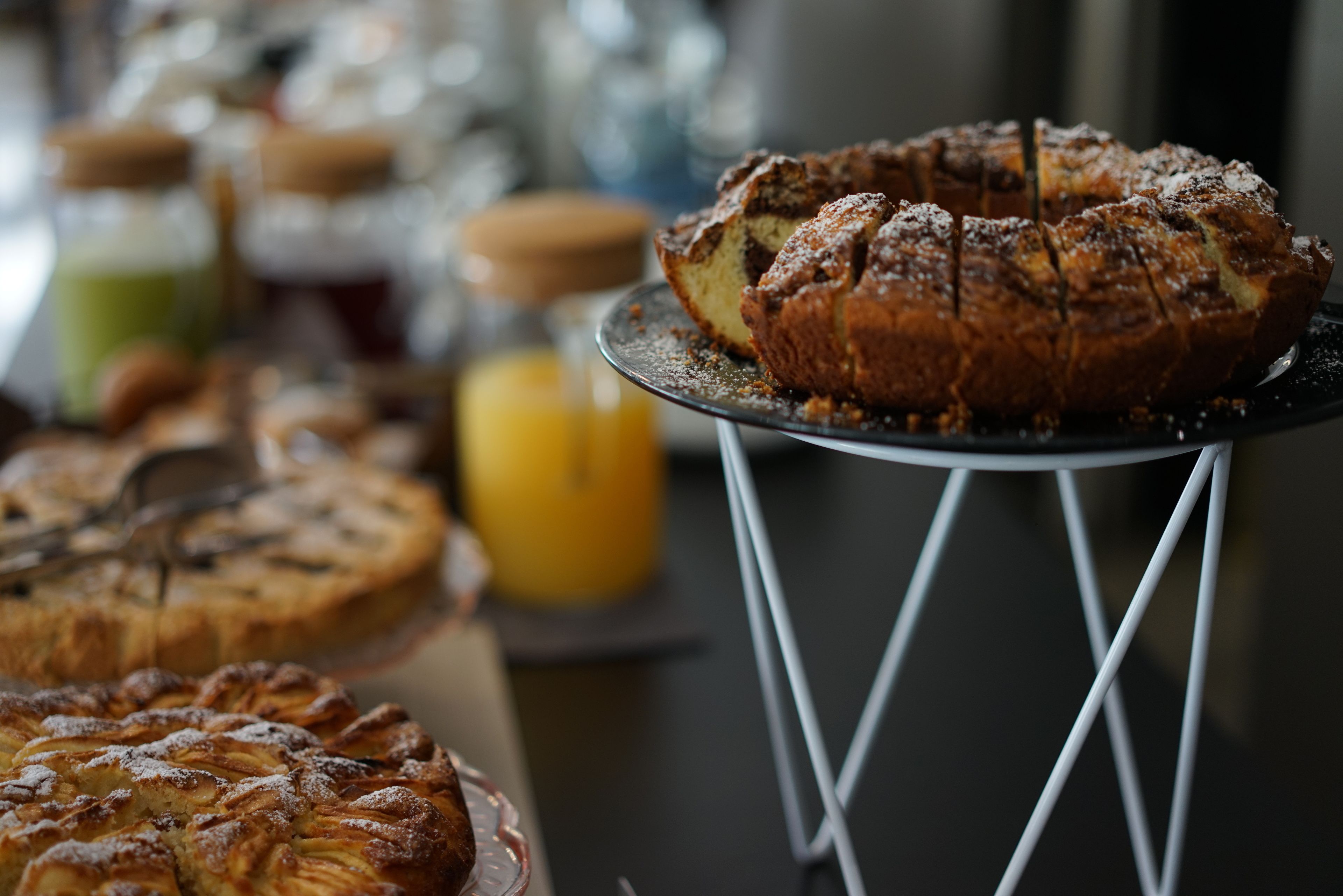 Verschiedene Backwaren liegen auf einem Tisch ausgestellt, darunter ein geflochtener Kuchen und ein Kuchen.